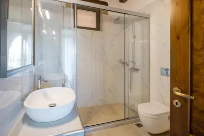 a bathroom with a shower and a toilet and a sink at Villa Kois by PosarelliVillas in Tzitzifés