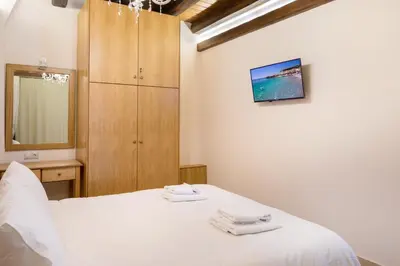 a bedroom with a white bed and a wooden cabinet at Villa Kois by PosarelliVillas in Tzitzifés