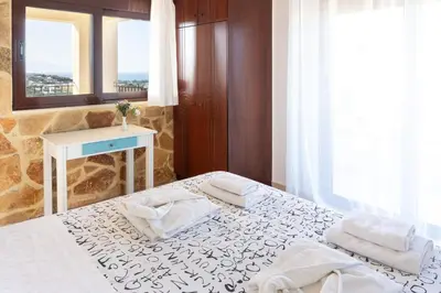 a bedroom with two beds and a table and a mirror at Pasiphae villas 1 & 2 in Stalos