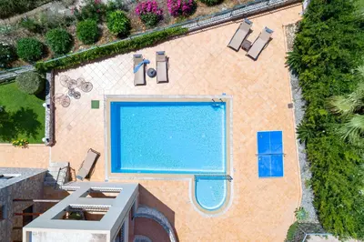 an overhead view of a swimming pool with two chairs at Pasiphae villas 1 & 2 in Stalos