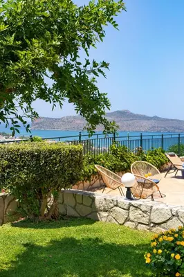 a patio with chairs and a tree and the water at Pasiphae villas 1 & 2 in Stalos