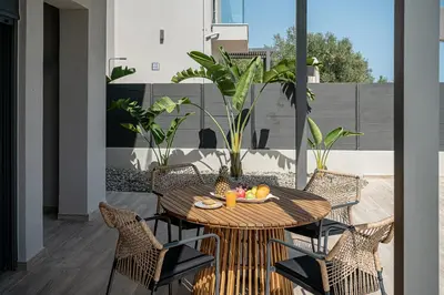 a patio with a table and chairs on a balcony at Melanthia Villas in Tsivarás