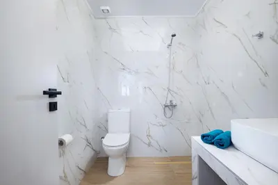 a white bathroom with a toilet and a sink at Villa Avo in Chania Town