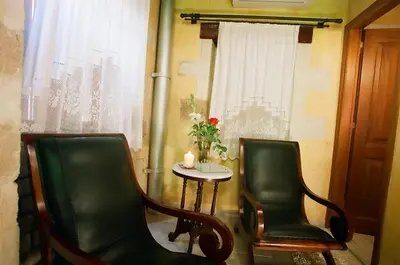 two chairs and a table with a candle and a window at IFIGENIA TRAD.ROOMS IN OLDTOWN BY.MARIOS in Chania Town