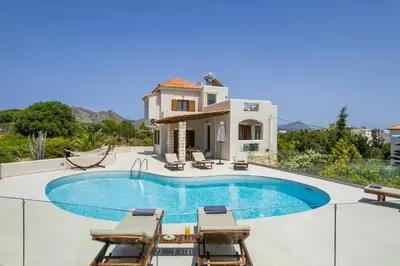 a swimming pool with chairs and a house at Seaview Villa Ormos, Heated Pool, Sea & Sun Villas in Chorafakia