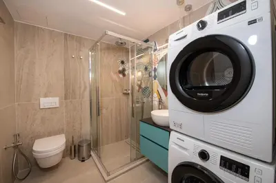 a bathroom with a toilet and a washing machine at Flos Apartments in Korakiaí