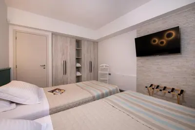 a bedroom with two beds and a tv on the wall at Flos Apartments in Korakiaí