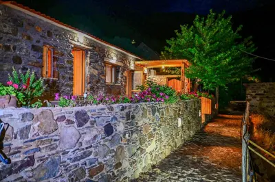 a stone house with flowers on a stone wall at Traditional Stone House with Mountain & Sea Views 