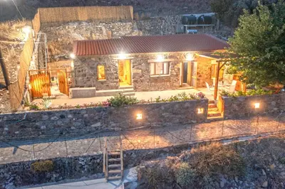 a small stone house with lights in front of it at Traditional Stone House with Mountain & Sea Views 