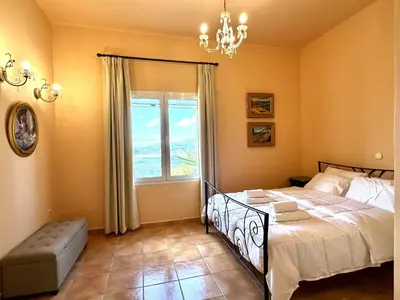 a bedroom with a bed and a window and a chandelier at Villa Kapodistria in Kallithea-Voukolies