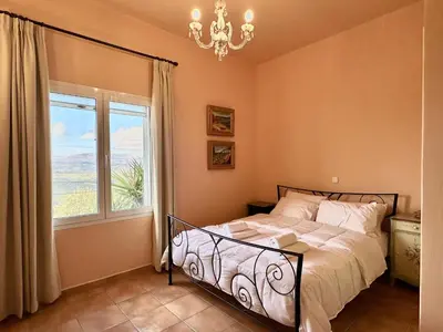 a bedroom with a bed and a window and a chandelier at Villa Kapodistria in Kallithea-Voukolies