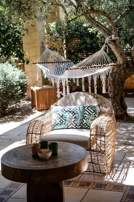 a wicker hammock chair and a table on a patio at Villa Dimi in Kalathas