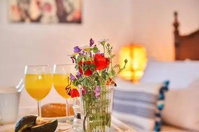a vase with flowers sitting on a table with two glasses at La Maison to Chani in Stílos