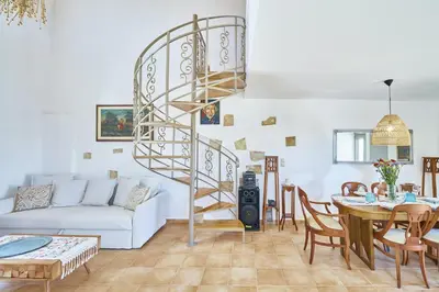 a living room with a spiral staircase and a table at La Maison to Chani in Stílos