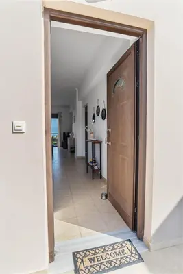 a hallway with a wooden door and a tile floor at Almyrida Bay View House II BY APOKORONAS-VILLAS in Almirida