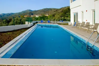 a swimming pool with chairs and a house at Kandania Paradise in Kántanos
