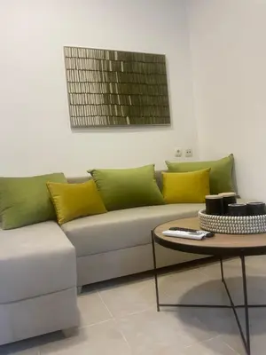 a couch with yellow and green pillows and a table at AIOLOS Chania center luxury apartment near the garden in Chania Town