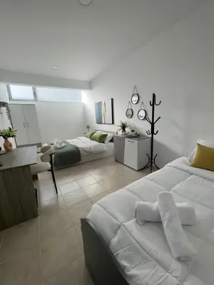 a white bedroom with a bed and a living room at AIOLOS Chania center luxury apartment near the garden in Chania Town