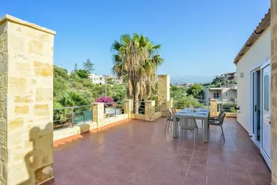 a patio with a table and chairs on a balcony at Elma's Villa: A peaceful, family-friendly place in Daratso
