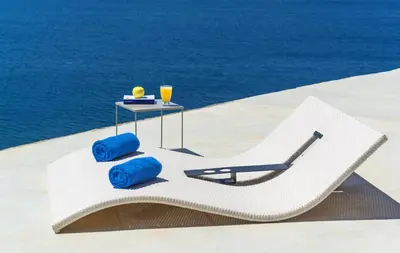 a white lounge chair and a table with blue pillows at Luxury seafront design villa Kyma in Tersanas Owner listing in Tersanas
