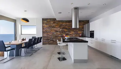 a kitchen with a table and chairs and a brick wall at Luxury seafront design villa Kyma in Tersanas Owner listing in Tersanas