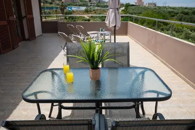 a glass table with two glasses of orange juice on a balcony at Garden House with Pool, 10min to center in Nerokoúros