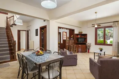 a living room with a table and chairs at Garden House with Pool, 10min to center in Nerokoúros