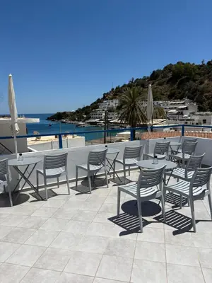 a patio with tables and chairs and the beach at Sofia Rooms in Loutro