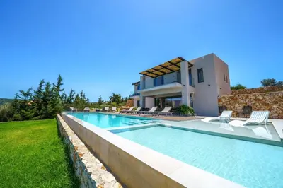 a villa with a swimming pool in front of a house at In Vivo Villa - Breathtaking View -90sqm Heated Infinity Pool in Áyios Pávlos