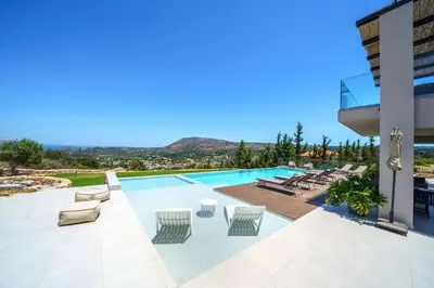 a swimming pool with lounge chairs and a building at In Vivo Villa - Breathtaking View -90sqm Heated Infinity Pool in Áyios Pávlos