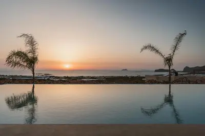 a swimming pool with palm trees in front of the ocean at Villa Aora Falassarna Beach I New luxury villa with infinity pool in Falasarna