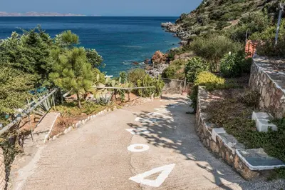 a dirt road next to the ocean with trees at 2 annexed apartments -Private place to swim-large terrace- Unlimited view in Ravdhoúkha