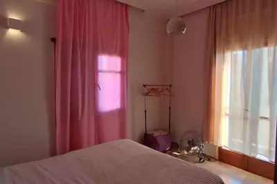 a bedroom with a bed and a window with pink curtains at Spacious Sunny house in Chania in Chania Town