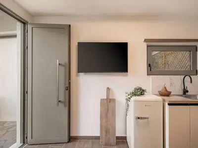 a kitchen with a refrigerator and a tv on the wall at Casa 28 City Apartments in Chania Town