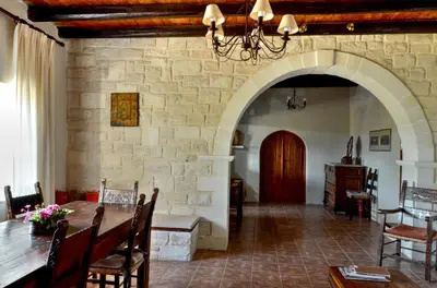 a dining room with a table and a stone wall at Anemole Traditional Cretan Villa in Megála Khoráfia