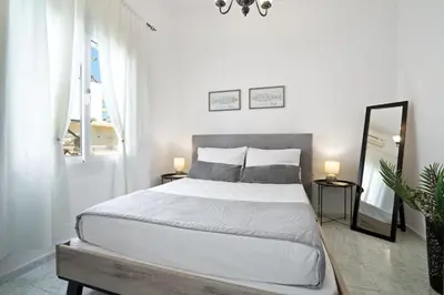 a white bedroom with a large bed and a mirror at Elie's House next to the beach in Chania Town