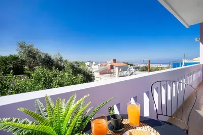 a table with two glasses of orange juice on a balcony at Home Philip III in Chania Town