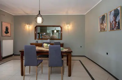 a dining room with a table and chairs and a mirror at Green Hill Villa in Daratso