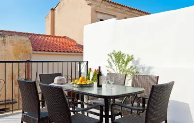 a table and chairs on a balcony with a bowl of fruit at Aphrodite House in Chania Town