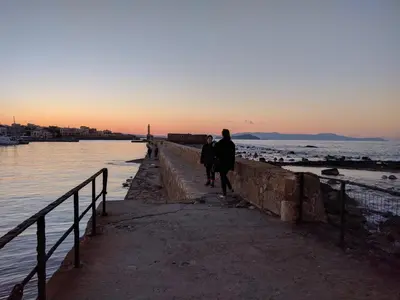 two people walking on a pier near the water at Rayon De Soleil in Chania Town