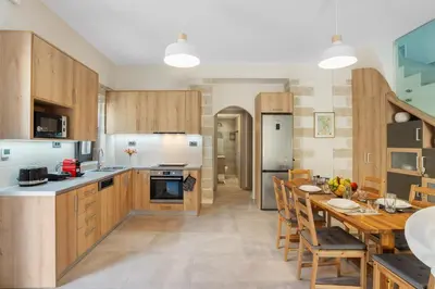 a kitchen with wooden cabinets and a table and a dining room at Brand new Villa Volakas BY APOKORONAS VILLAS in Gavalochori