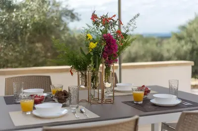 a table with flowers in vases and plates on it at Brand new Villa Volakas BY APOKORONAS VILLAS in Gavalochori