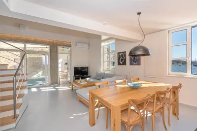 a dining room and living room with a wooden table and chairs at Hippocampo Waterfront Villa in Chania Town