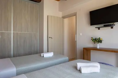 a bedroom with two beds and a flat screen tv at Villa Forteza in Kalami