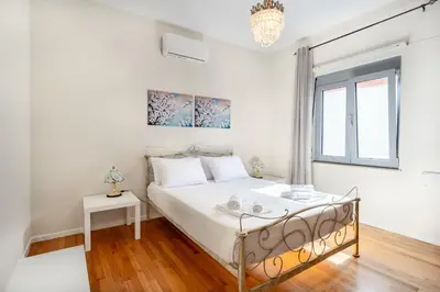 a white bedroom with a bed and a window at Suncatcher House by 8essentially in Chania Town