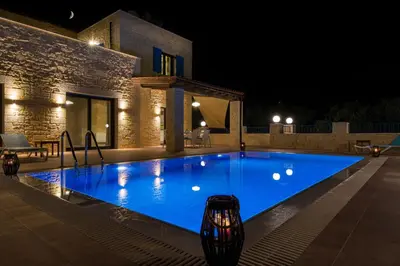 a large blue swimming pool at night at Villa Aliki - Traditional stone house with maximum privacy and stunning views ! in Xamoudhokhórion