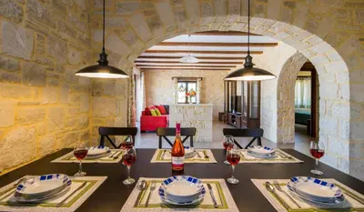 a dining room with a table with glasses of wine at Villa Aliki - Traditional stone house with maximum privacy and stunning views ! in Xamoudhokhórion