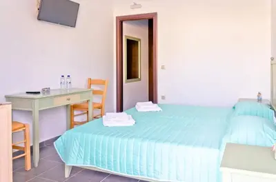 a bedroom with a bed and a desk and a table and chair at On the Beach in Kissamos