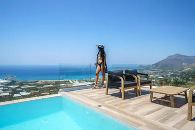a woman standing on the edge of a swimming pool at NAFSIKA XENIA-VILLA ARGO in Plátanos