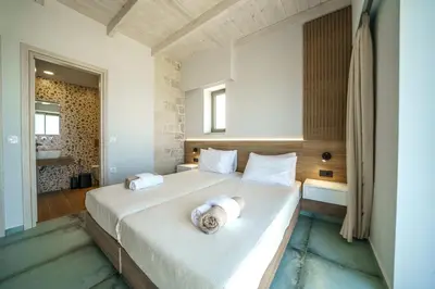 a bedroom with a large bed with towels on it at NAFSIKA XENIA-VILLA ARGO in Plátanos